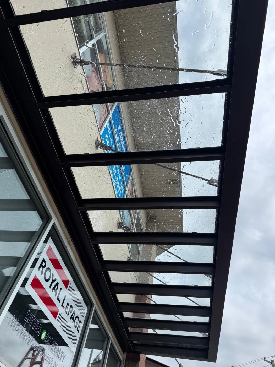 The same awning glass washed clear, water still beading on the surface.