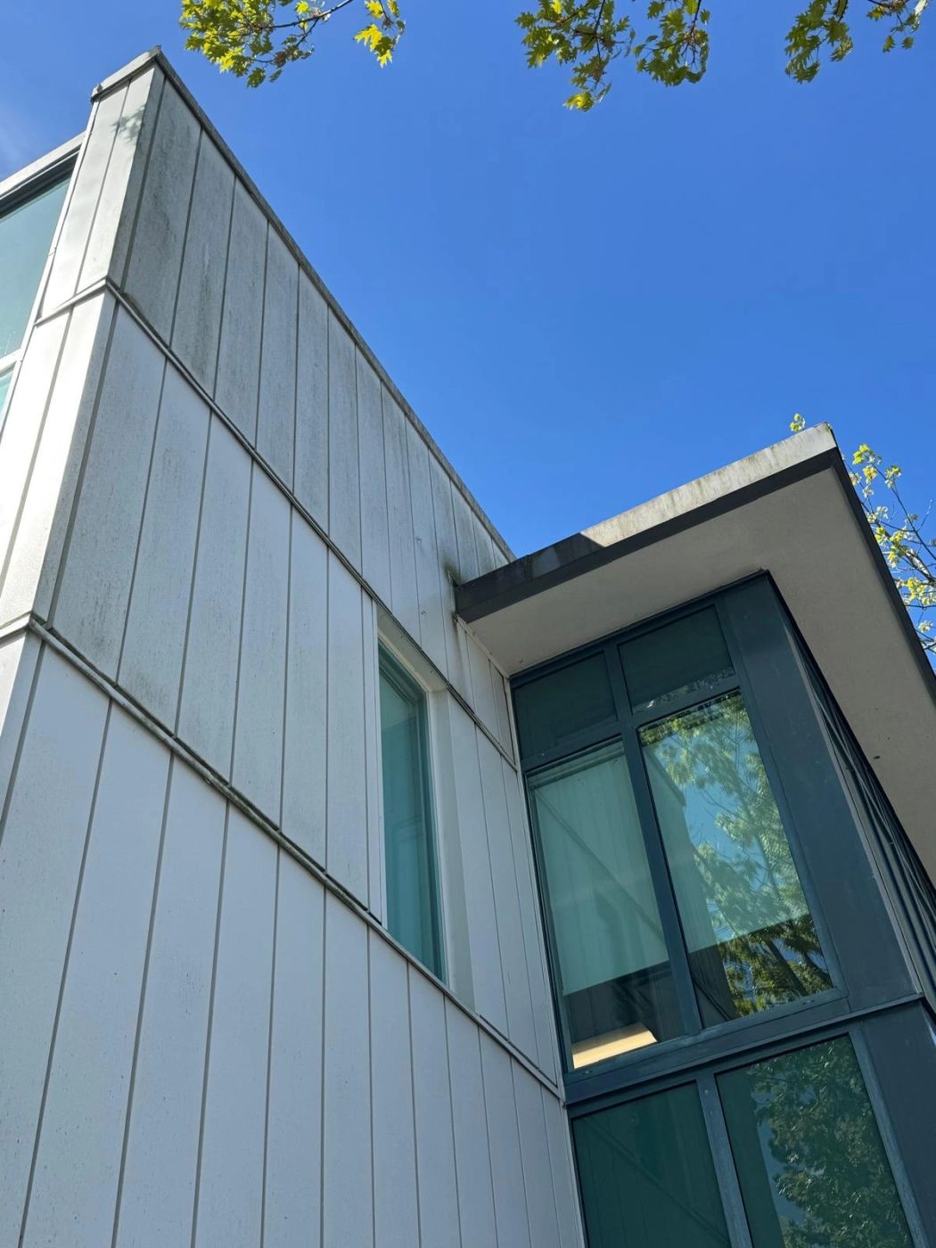 Looking up the panelled side of a Lower Mainland commercial building against a clear blue sky.