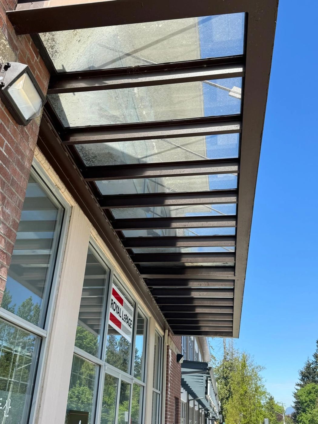 Storefront awning glass heavily clouded with algae and mineral staining.